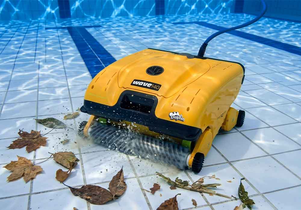 Dolphin Wave 140 scrubbing leaves off a tiled commercial pool floor